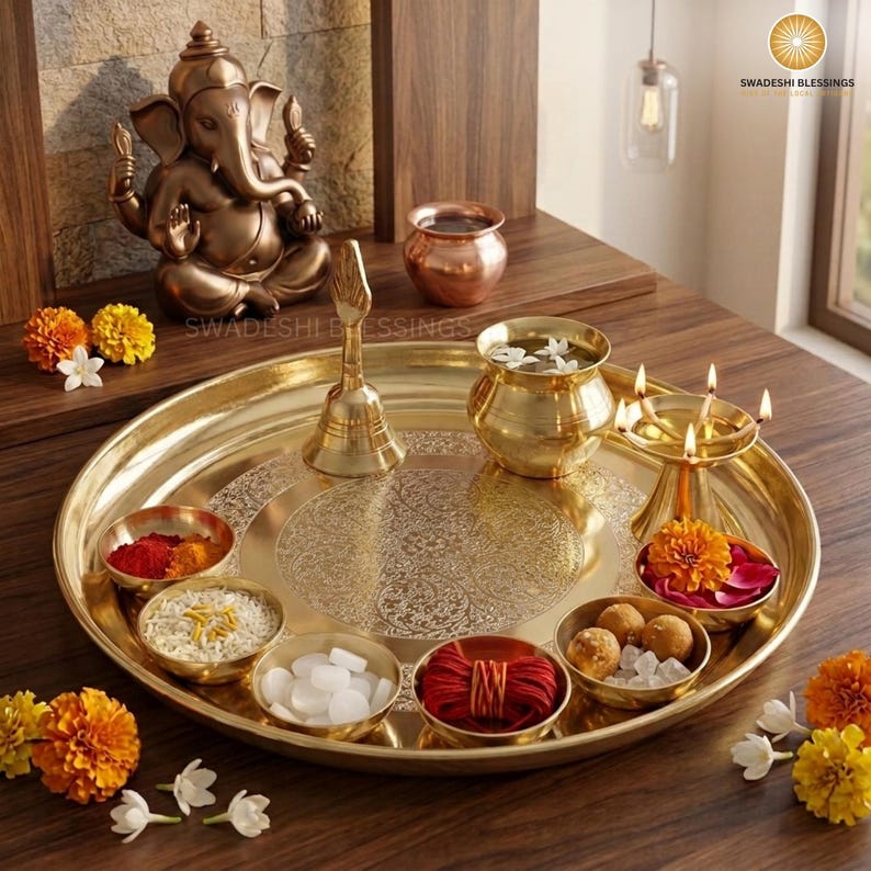 May include: A golden brass puja thali with a lit candle, small bowls of spices and nuts, a bell, and red roses. The thali is round and has an engraved design.