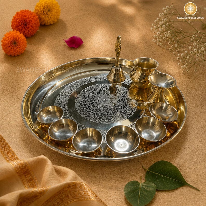 May include: A golden brass puja thali with a lit candle, small bowls of spices and nuts, a bell, and red roses. The thali is round and has an engraved design.