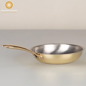 May include: A gold hammered stainless steel frying pan with a long handle. The pan has a silver interior.