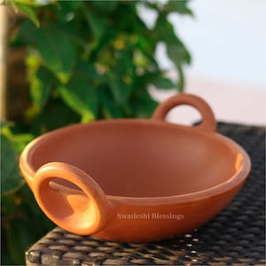 May include: A terracotta serving bowl with two handles. The bowl is a reddish-brown colour and has a smooth, slightly glossy finish. The bowl is labelled "Swadeshi Blessings".