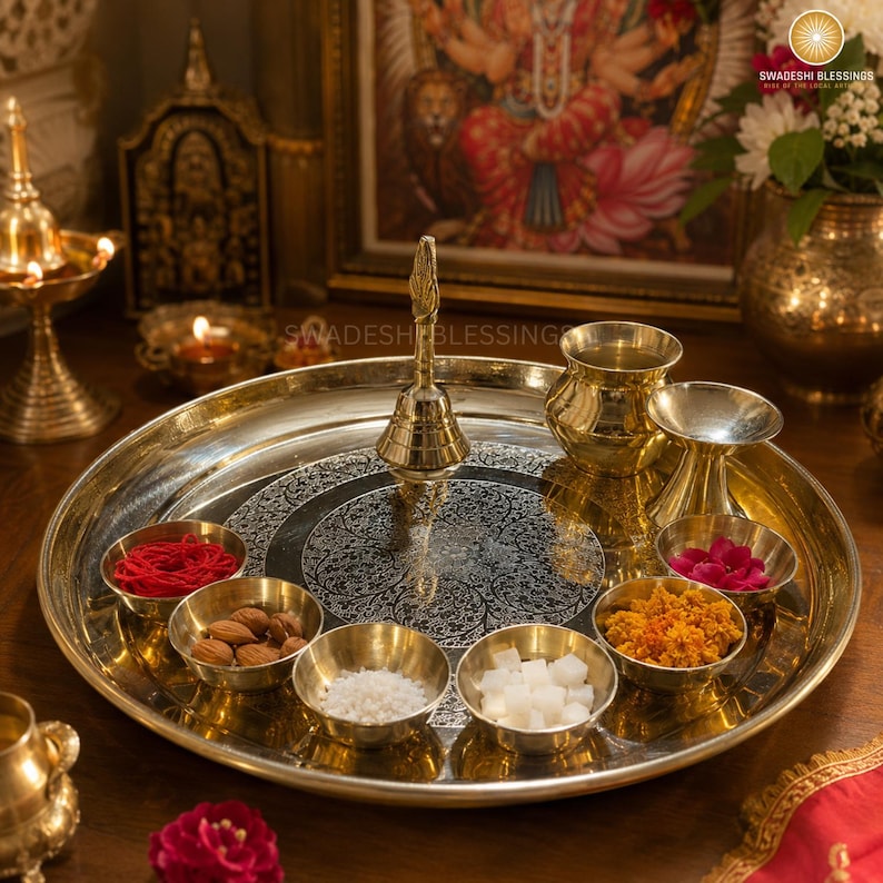 May include: A golden brass puja thali with a lit candle, small bowls of spices and nuts, a bell, and red roses. The thali is round and has an engraved design.