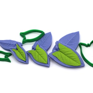May include: A set of six leaf-shaped silicone molds for baking and decorating cakes. The molds are in two colors: purple and green. The molds are designed to create realistic-looking leaves.