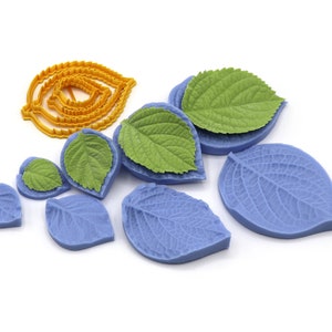 Puede incluir: Un conjunto de moldes y cortadores con forma de hoja de varios tamaños. Los moldes son de color azul claro y las hojas verdes. También se incluye un juego de cortadores amarillos con forma de hoja, ideal para manualidades y repostería.
