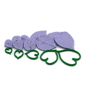 May include: A collection of lavender-colored leaf-shaped and heart-shaped molds and green leaf and heart-shaped cookie cutters. The molds and cutters are arranged on a white background, ideal for crafting or baking.