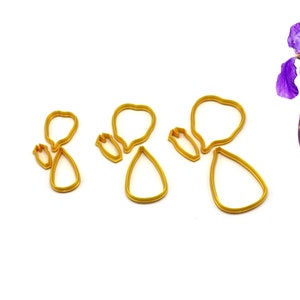 Peut inclure: Ensemble de trois emportes-pièces en métal de couleur dorée en forme de fleurs d'iris. Les emportes-pièces sont de tailles différentes et présentent un design détaillé.