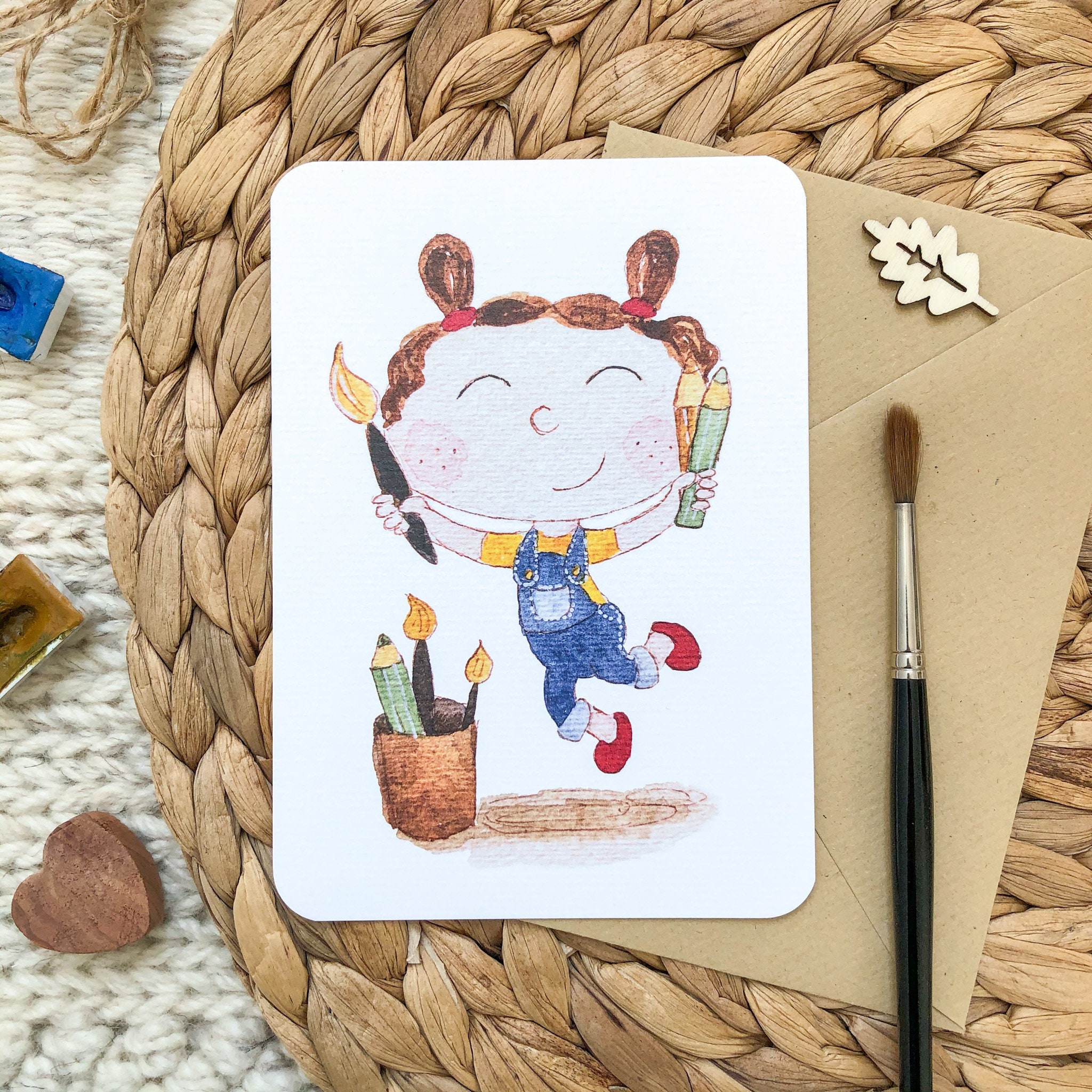 Hand-drawn postcard with a joyful girl jumping with a paint brush and colour pencils Hand-drawn postcard with a joyful girl jumping with a paint brush and colour pencils