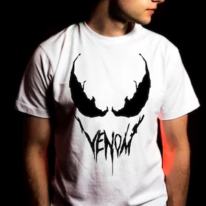 May include: White t-shirt with a black Venom graphic. The graphic features the iconic Venom eyes and the word "VENOM" in a dripping font.