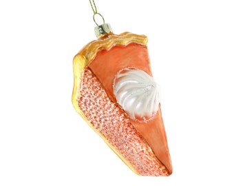 Peut inclure: Ornement en forme de part de tarte avec une garniture orange et une garniture de crème fouettée blanche. La croûte est brun doré et le côté de la tarte est recouvert de paillettes. Une boucle métallique dorée est attachée pour l'accrocher.