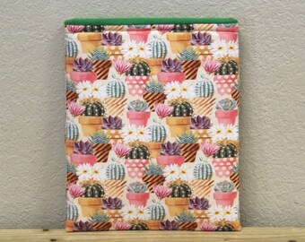 May include: A green and white fabric pouch with a cactus print. The pouch is made of a soft, quilted fabric and has a zipper closure.