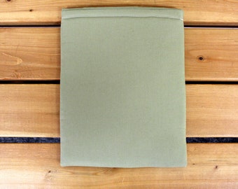 May include: A light green fabric pouch with a sewn seam around the top edge. The pouch is lying flat on a wooden surface.