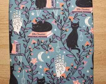 May include: A teal book sleeve featuring a repeating pattern of black cats, floral vines, moons, and palmistry hands. The design includes the text "The Occultist [Practical Potions]" and "Palmistry" on book spines.