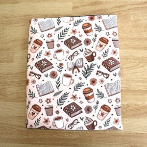 May include: A rectangular book cover with a white background, featuring a repeating pattern of books, coffee cups, eyeglasses, flowers, and leaves in shades of brown, pink, and green. The cover is designed for books and offers protection.