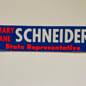 May include: A blue and white political campaign sign with the text "Mary Jane Schneider State Representative".
