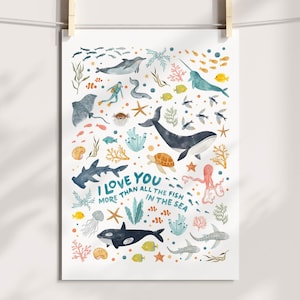 May include: A watercolor print featuring various marine animals, including a whale, shark, and octopus, with the text "I love you more than all the fish in the sea." The artwork is in shades of blue, green, and orange, and is hanging from a clothesline.