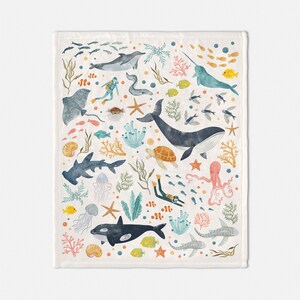 May include: A colorful illustration of various sea creatures, including a whale, a narwhal, a stingray, a sea turtle, a jellyfish, a starfish, and a diver. The illustration is set against a light beige background with coral and seaweed.