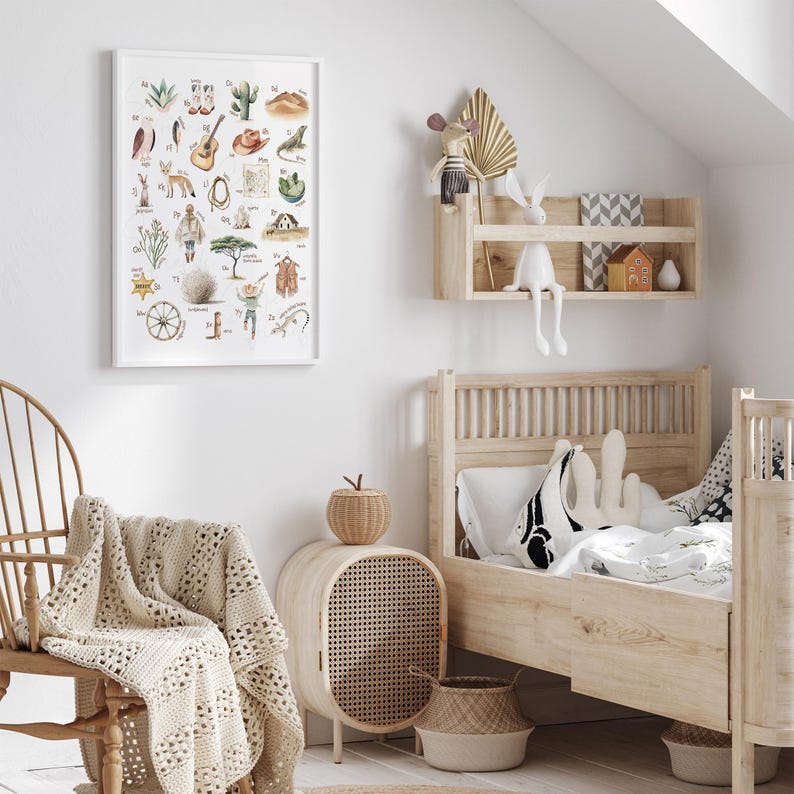 May include: A children's bedroom scene with a framed alphabet print, a wooden bed, and a woven chair. The print features watercolor illustrations of objects. A woven blanket and a small side table with a woven front add to the room's decor.