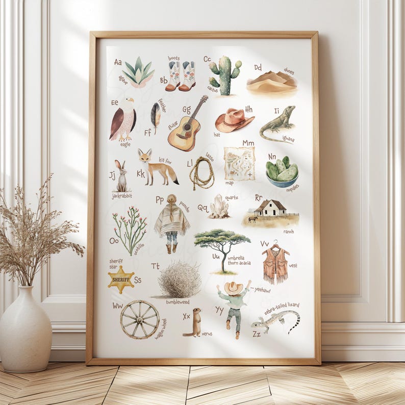 May include: A framed watercolor print featuring a Western-themed alphabet. Each letter is paired with an illustration, including a cactus, cowboy boots, a guitar, a lizard, and a sheriff's badge. The print has a wooden frame.