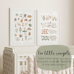 May include: Two framed watercolor prints with a western theme. One features the alphabet with cowboy-related illustrations, the other displays numbers 1-10 with corresponding images. The prints are in white frames.