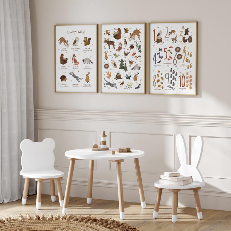 May include: A white wooden table and two chairs with bunny and bear ear accents. The table has a white top and wooden legs. The chairs have white seats and wooden legs. There are three framed posters on the wall behind the table. The posters feature illustrations of animals and numbers.