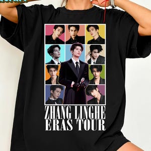May include: Black t-shirt featuring a colorful grid of nine images of a man, with a central image of the same man in a suit holding a microphone. The text "ZHANG LINGHE ERAS TOUR" is printed below the images.