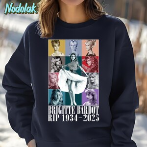 K&ouml;nnte beinhalten: Marineblaues Sweatshirt mit einer Collage von Bildern von Brigitte Bardot in verschiedenen Posen und Farben. Der Text "BRIGITTE BARDOT RIP 1934-2025" ist darunter gedruckt. Das Sweatshirt hat einen Rundhalsausschnitt und lange &Auml;rmel.