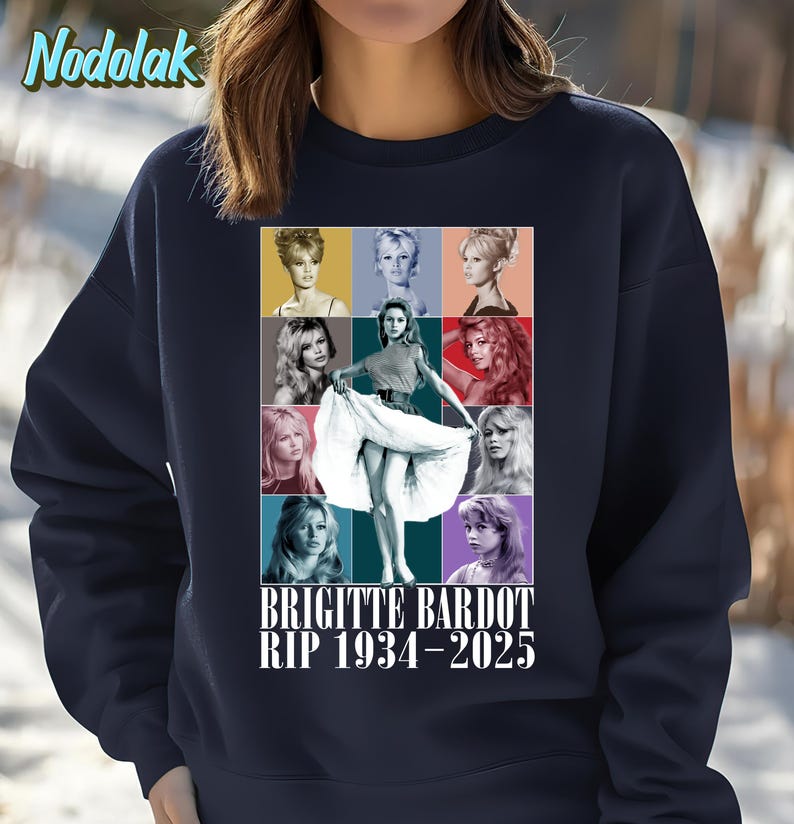 K&ouml;nnte beinhalten: Marineblaues Sweatshirt mit einer Collage von Bildern von Brigitte Bardot in verschiedenen Posen und Farben. Der Text "BRIGITTE BARDOT RIP 1934-2025" ist darunter gedruckt. Das Sweatshirt hat einen Rundhalsausschnitt und lange &Auml;rmel.