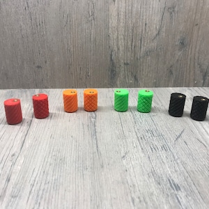 May include: Eight small, cylindrical knobs in various colors, including red, orange, green, and black. The knobs have a textured surface and a small hole in the top.