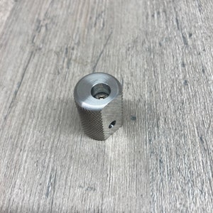 May include: A silver metal knob with a textured surface and a small hole in the center.