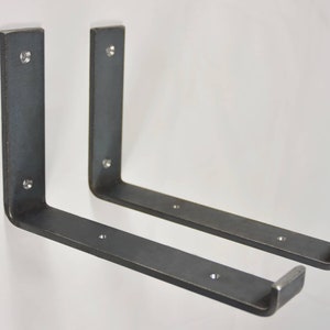 May include: Two black metal shelf brackets with a 90-degree angle. The brackets are made of sturdy metal and have a rustic finish.