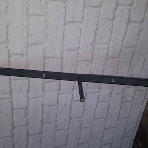 May include: Black metal shelf brackets mounted to a white brick wall. The brackets are designed to support a shelf or other hanging objects.