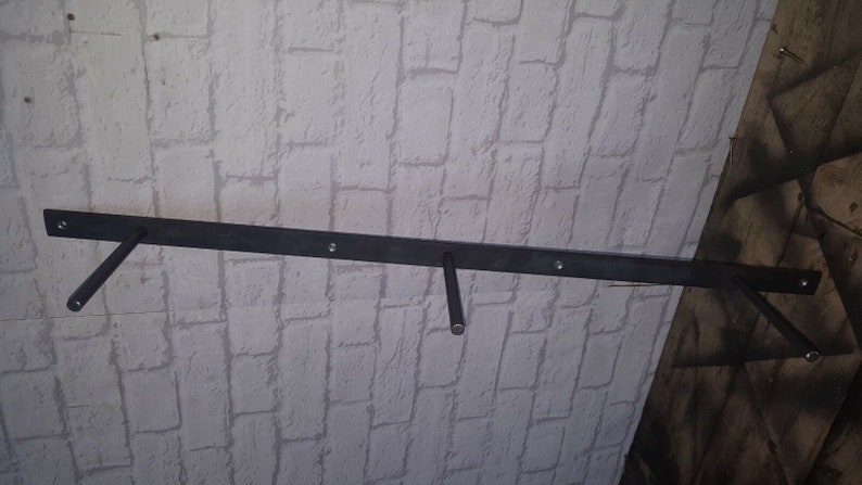 May include: Black metal shelf brackets mounted to a white brick wall. The brackets are designed to support a shelf or other hanging objects.