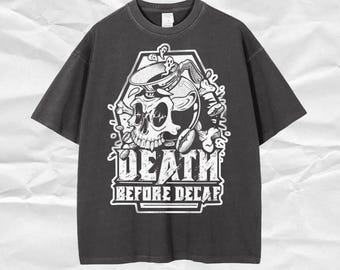 Może przedstawiać: Ciemnoszara koszulka z czarno-białą grafiką. Projekt przedstawia czaszkę, ekspres do kawy i napis "DEATH BEFORE DECAF". Tekst jest pogrubiony i stylizowany. Koszulka ma krótkie rękawy i okrągły dekolt.