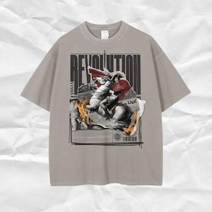 May include: A gray t-shirt with a graphic print of a man on horseback. The graphic includes the word "Revolution" and the text "Viva La" and "King Up!" The graphic is surrounded by a black border.