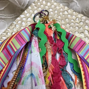 May include: A colorful key chain with a variety of ribbons, trims, and fabrics. The key chain features a rainbow design and a metal ring.