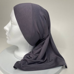 May include: A charcoal grey jersey knit hijab with a long, flowing design. The hijab is made of a soft, stretchy fabric and is perfect for everyday wear.