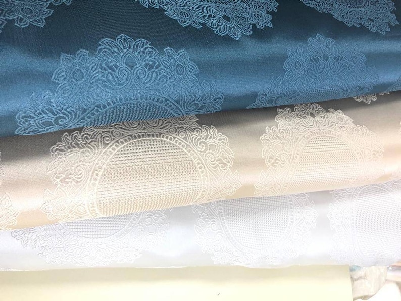 May include: Three fabric swatches with a white damask pattern. The top swatch is teal blue, the middle swatch is beige, and the bottom swatch is white.