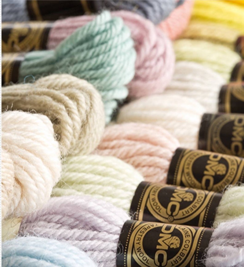 Peut inclure: Gros plan sur une vari&eacute;t&eacute; de bobines de fil &agrave; broder DMC dans des couleurs pastel, notamment bleu clair, lavande, vert p&acirc;le, beige et cr&egrave;me. Les bobines sont dispos&eacute;es en rang&eacute;e, avec le logo et la marque DMC visibles sur chaque bobine.