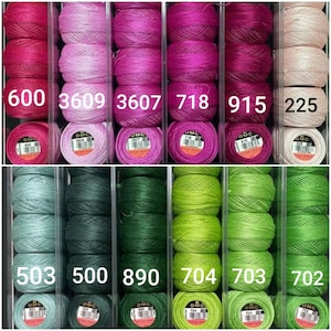 May include: Six spools of DMC embroidery floss in shades of pink, red, and beige, with the DMC numbers 600, 3609, 3607, 718, 915, and 225 printed on the labels. Six spools of DMC embroidery floss in shades of green, with the DMC numbers 503, 500, 890, 704, 703, and 702 printed on the labels.