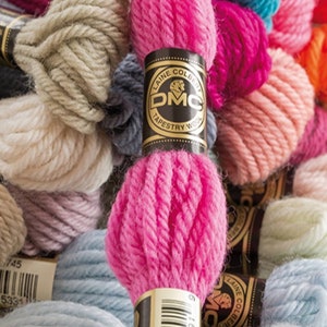 Peut inclure: Gros plan sur une vari&eacute;t&eacute; de pelotes de laine color&eacute;es, dont du rose, du bleu, du beige et du blanc. La laine est &eacute;tiquet&eacute;e "DMC Tapestry Wool" et est dispos&eacute;e en pile.