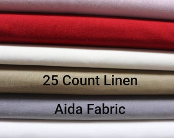 Può includere: Un mucchio di tessuti diversi, tra cui un tessuto di lino beige etichettato "25 Count Linen" e un tessuto Aida grigio.