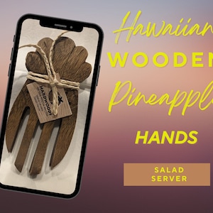 May include: Wooden salad servers shaped like pineapple hands. The servers are made of dark brown wood and are tied together with twine. The servers are labeled "Hardwoods of the South Pacific" and "Salad Servers".
