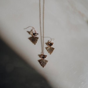 Puede incluir: Un collar y pendientes a juego de oro con un dise&ntilde;o geom&eacute;trico en forma de abanico y un acento de cristal transparente.