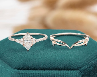 May include: A rose gold engagement ring set with a marquise cut diamond and a matching rose gold wedding band with a delicate design.