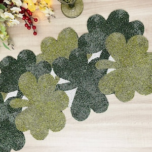 May include: A green and white beaded table runner with a clover leaf design.
