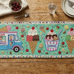 Puede incluir: Un camino de mesa bordado con temática de helados. El camino de mesa presenta un camión de helados, conos de helado y helados, todo en colores brillantes. El texto "Ice Cream Scoops & Smiles" está en el camión.