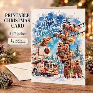 Könnte beinhalten: Eine druckbare Weihnachtskarte im Format 12,7 x 17,8 cm mit einer Aquarellillustration von Lebkuchenfiguren, die an einem Strommast mit bunten Lichterketten arbeiten. Der Text lautet PRINTABLE CHRISTMAS CARD und Merry Christmas.