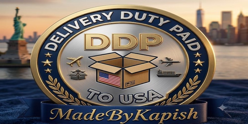 Puede incluir: Un emblema met&aacute;lico circular con borde dorado y centro plateado que presenta el texto DELIVERY DUTY PAID DDP TO USA. El dise&ntilde;o incluye una caja de cart&oacute;n con una bandera de EE. UU., iconos de aviones y un barco, y el texto MadeByKapish en una cinta azul.