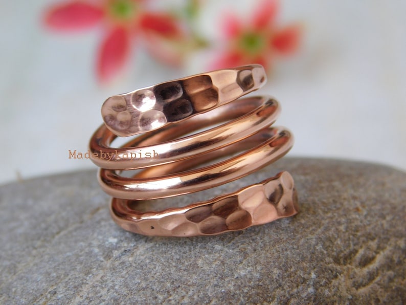 May include: A copper ring with a hammered finish. The ring is made of four bands of copper that are twisted together. The ring is a warm copper colour.