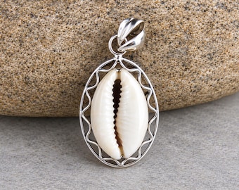 May include: A silver pendant featuring a central white cowrie shell encased in a polished oval frame with a wavy wire border. The pendant includes a smooth, rounded silver bail at the top for attachment to a chain or cord necklace.