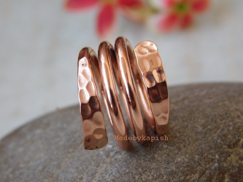 May include: A hammered copper ring with a spiral design. The ring is made of multiple bands of copper that are twisted together. The ring is a warm copper colour and has a rustic look.